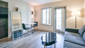 Un salon moderne comprenant un canapé, une table basse ronde, une table à manger avec des chaises et un grand miroir.