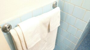 A bathroom with blue tiles and a white towel hanging on a chrome towel rack. - Natural Home (Firenze)
