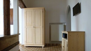 A room with a large wooden wardrobe, a small wooden cabinet, and a radiator on the wall. - Natural Home (Firenze)