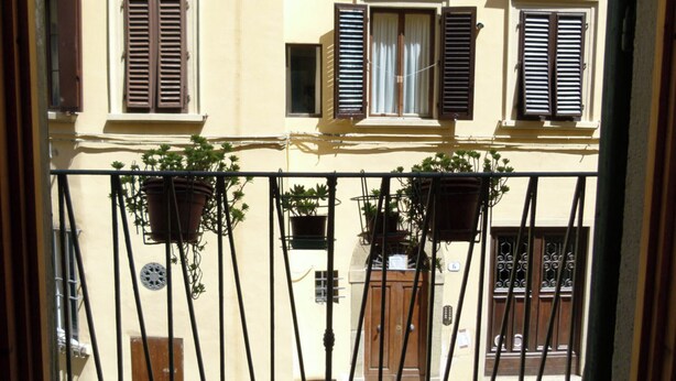 A balcony with potted plants and a wooden door. - Natural Home (Firenze)
