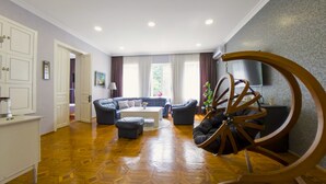Amplia sala de estar con piso de madera, sofá, mesa de centro y una original mecedora de madera.
