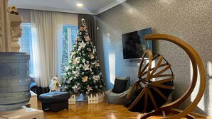 Una sala de estar con un árbol de Navidad, un dispensador de agua, una silla de madera y un tapete estampado.