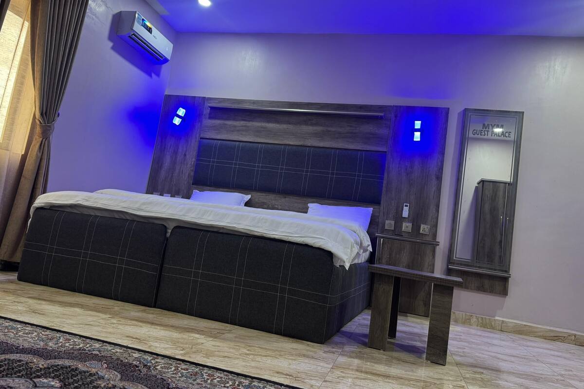 Un dormitorio moderno con una cama grande, una mesita de noche, un espejo y un equipo de aire acondicionado.