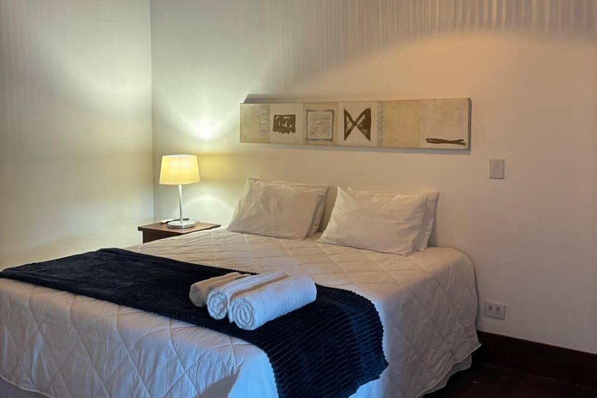 Een slaapkamer met een groot bed, een bedlampje en een hangende lamp.