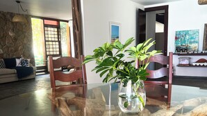Un coin repas comprenant une table à plateau de verre, une chaise en bois et une plante en pot.