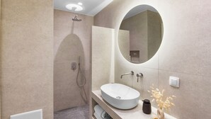Une salle de bain moderne avec un grand miroir ovale, un lavabo blanc et une douche.