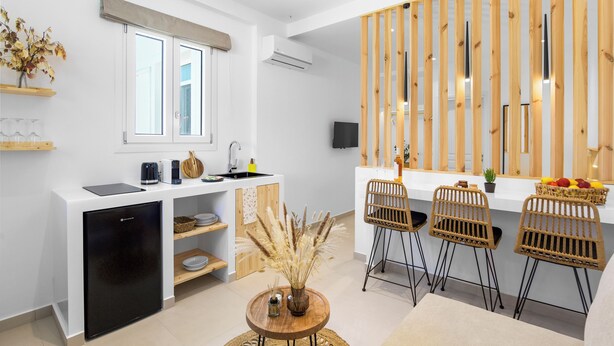 Une cuisine moderne avec des meubles blancs, un lave-vaisselle intégré et un coin repas en bois avec des chaises en osier.
