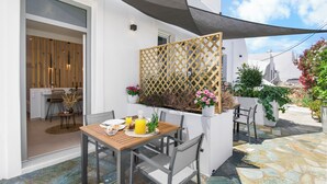 Une terrasse avec une table et des chaises en bois, une boisson jaune et des plantes en pot.