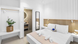 Une chambre d’hôtel moderne avec un grand lit, une table de chevet, une commode, un miroir et une plante posée sur une étagère.
