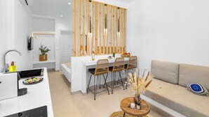 Une cuisine moderne avec un plan de travail blanc, des chaises en bois et un coin repas.