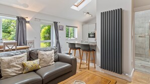 Ein modernes Wohnzimmer mit einer Couch, einem Couchtisch und einer Küchenzeile mit Esstisch und Stühlen.