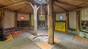 Ein rustikales Interieur mit freiliegenden Holzbalken, Steinwänden und einer zentralen Holzsäule.
