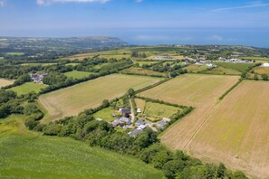 An aerial view of a rural area with fields, a small cluster of buildings, and a large white barn. - Hedgerow at Gorslwyd - Sound Retreat (Cardigan)