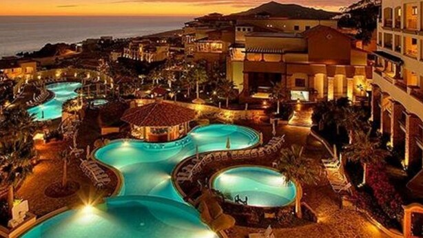 Un resort con varias piscinas, vistas a la playa y arquitectura de estilo mediterráneo.