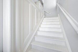 A white staircase with a handrail and a door on the left.