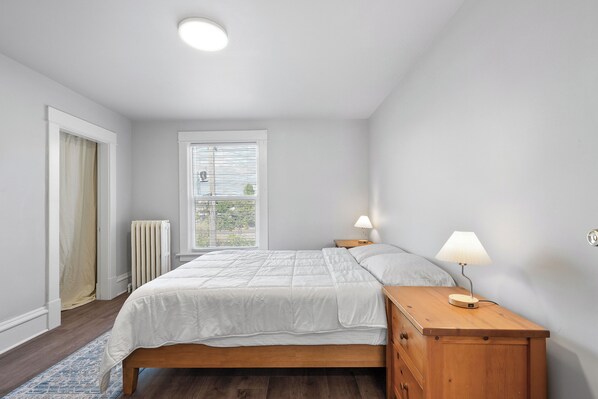 A bedroom with a bed, bedside tables, a window, and a radiator.