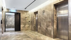 A modern elevator area with marble walls and a polished floor, featuring elevators marked with the number 13.
