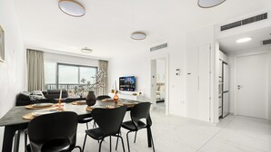 A modern dining area with a marble floor, black chairs, and a dining table set for four.