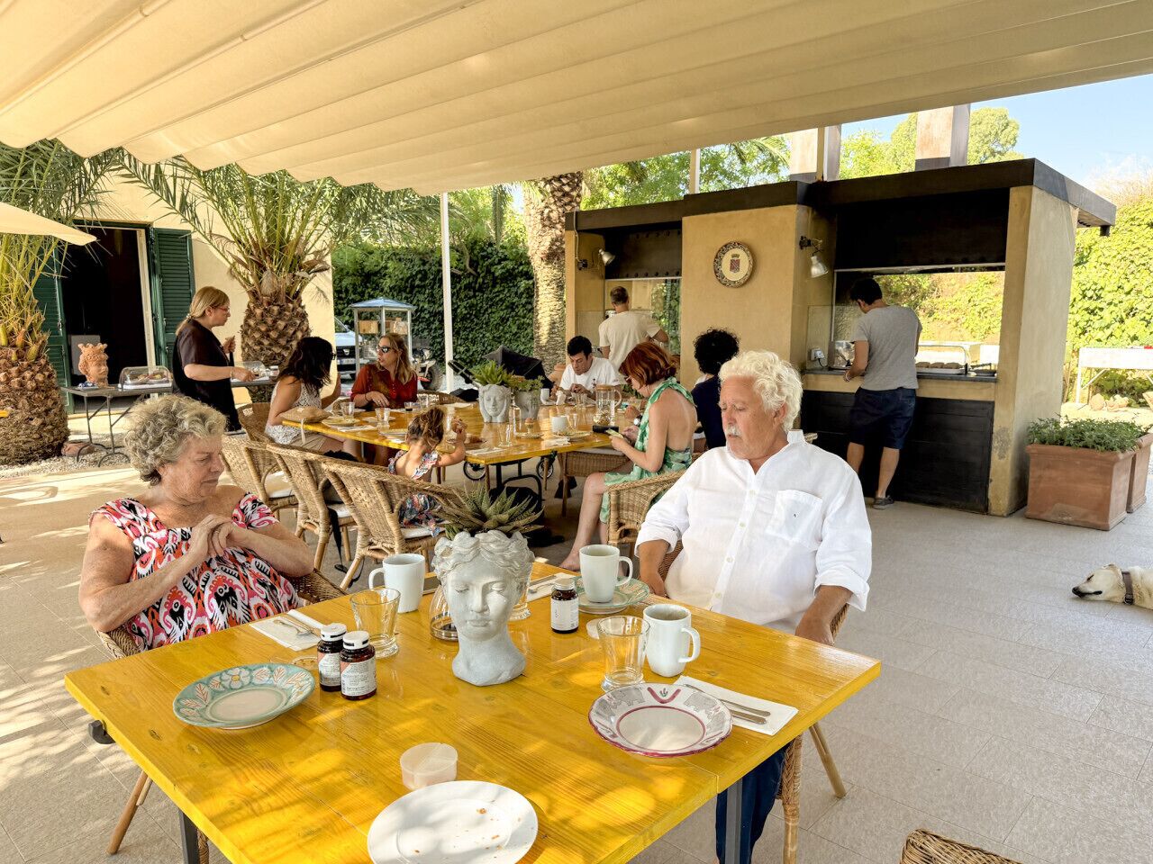 An outdoor dining area with tables, chairs, and a grill station.