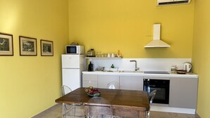 A compact kitchen with a dining table, chairs, a microwave, a sink, and an oven.