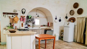 A kitchen with a central island, white cabinets, a stove, and a refrigerator. - Masseria PietraViva - Altamura (Altamura)
