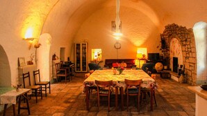 A cozy, rustic dining room with a stone fireplace, a piano, and a fireplace mantle. - Masseria PietraViva - Altamura (Altamura)