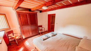 A bedroom with a wooden bed frame, a wooden chair, a wardrobe, and a door. - Podere tra gli Ulivi - Double Room Apartment (Parrano)