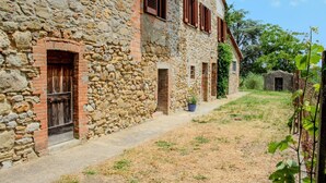 A stone building with a rustic exterior, featuring a small garden area with a potted plant and a pathway leading to the entrance. - Podere tra gli Ulivi - Double Room Apartment (Parrano)