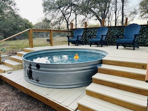 A hot tub on a wooden deck with steps leading up to it, surrounded by blue Adirondack chairs. - Enchanting Magical Modern Tiny Home; pet friendly (New Braunfels)