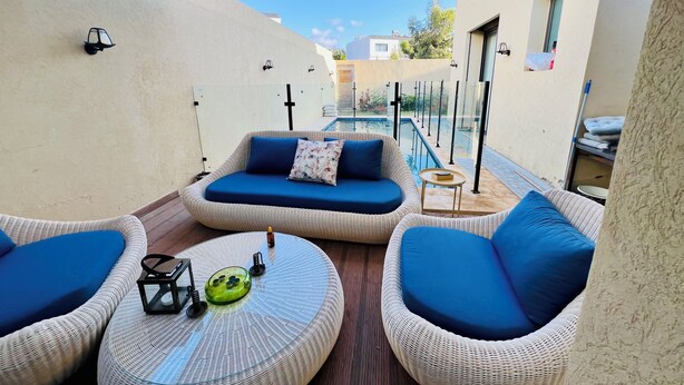 Una terraza en la azotea con mobiliario de mimbre, una piscina y vistas despejadas de los edificios circundantes.