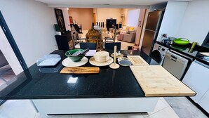 Une cuisine moderne avec un plan de travail noir, une planche à découper en bois et divers ustensiles de cuisine.