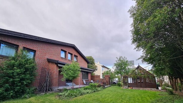 Un quartier résidentiel comprenant une maison en briques, une petite construction en bois et une pelouse bien entretenue.