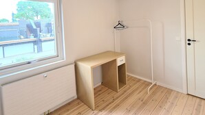 Une pièce avec un bureau en bois, un radiateur, une fenêtre et une porte.