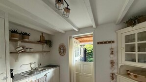 Una cocina con armarios blancos, un lavamanos y un ventanal con vistas al verdor exterior.