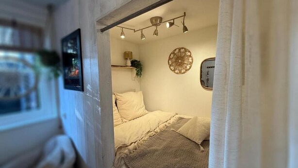 Un dormitorio acogedor con cama, una lámpara colgante y un adorno de pared.