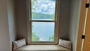 Une baie vitrée avec un banc intégré, offrant une vue sur un lac et une forêt.