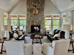 A spacious living room with a stone fireplace, leather sofas, and a television.
