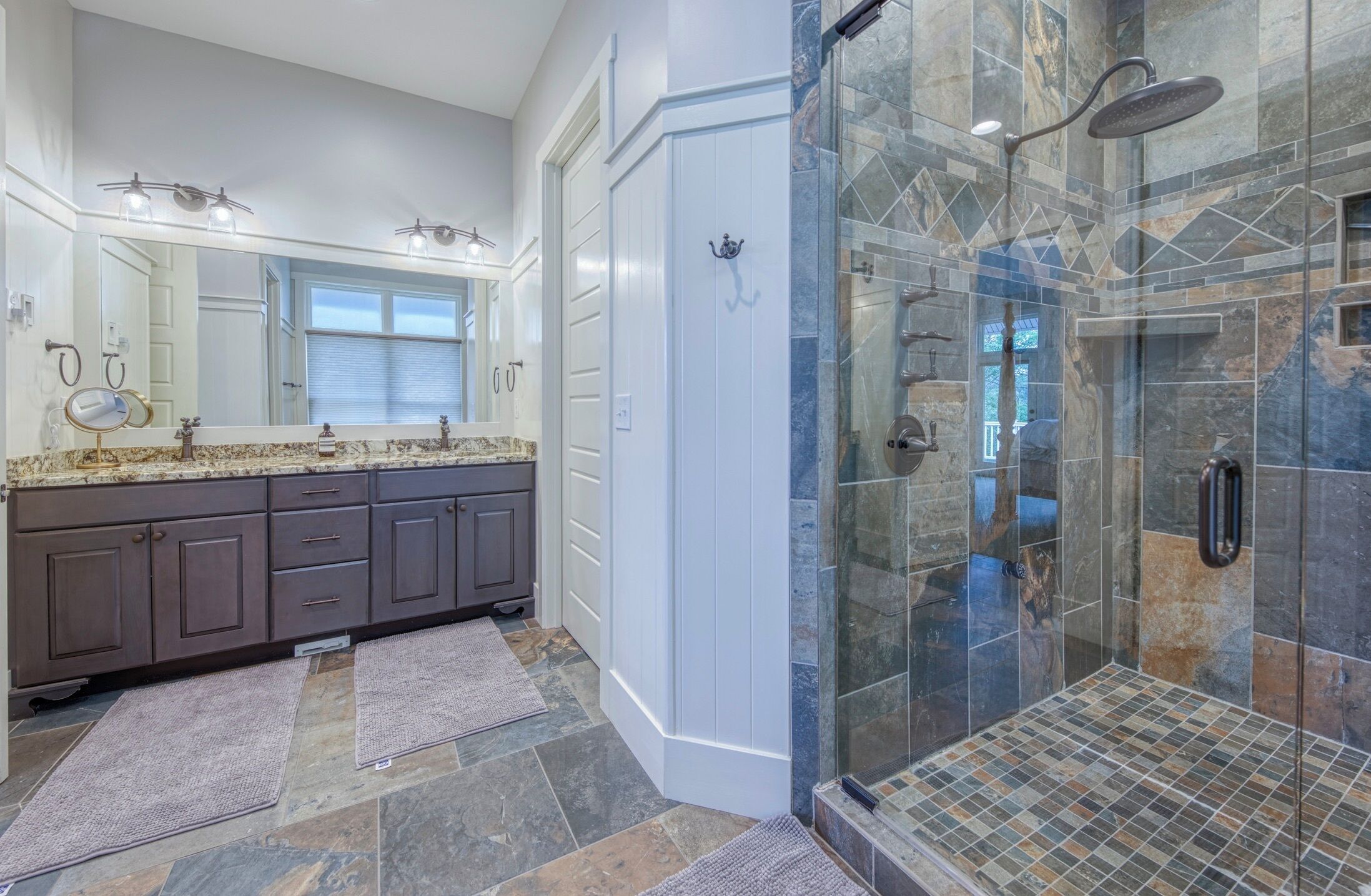 A modern bathroom with a double vanity, a glass shower enclosure, and a large mirror.