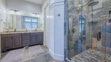 A modern bathroom with a double vanity, a glass shower enclosure, and a large mirror.