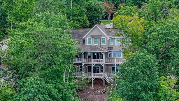 Une maison avec un quai et une rampe pour bateaux, entourée d’une forêt dense.