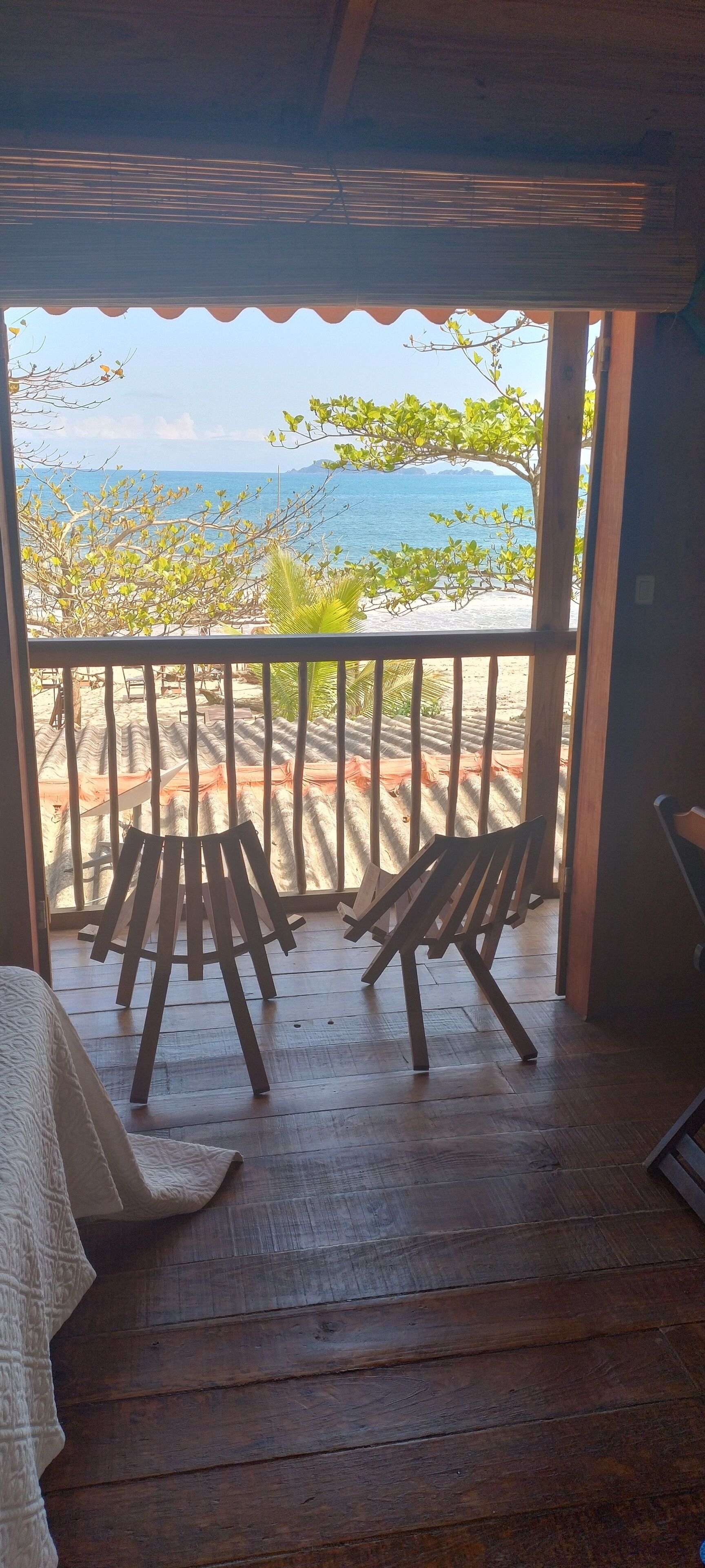 En träveranda med stolar och utsikt över havet.