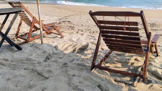 A beach with wooden lounge chairs and a large umbrella. - Shambhala Ecological Suite by the Sea between Paraty and Ubatuba (Camburi Ubatuba)