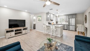 A modern living room with a flat-screen TV, a coffee table with a plant, and a blue sofa. - CRYSTAL BEACH GETAWAY-STEPS TO THE GULF (Crystal Beach)