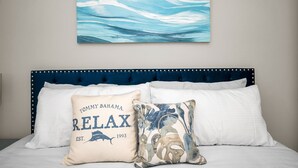 A bedroom with a blue upholstered headboard, a white bedspread, and two decorative pillows. - CRYSTAL BEACH GETAWAY-STEPS TO THE GULF (Crystal Beach)