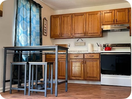 A kitchen with wooden cabinets, a gas stove, a microwave, and a coffee maker.