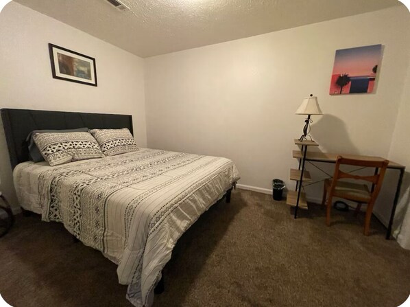 A bedroom with a bed, a desk, and a chair.