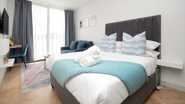 A modern hotel room with a large bed, a desk, and a chair.