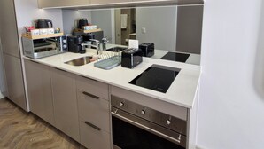 A modern kitchen with stainless steel appliances, a built-in oven, and a countertop with a coffee maker and toaster.