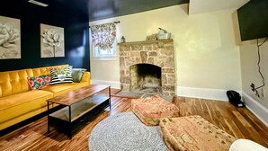 A living room with a yellow sofa, a stone fireplace, and a coffee table.