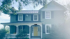 A two-story house with a porch, a front door, and a chimney.